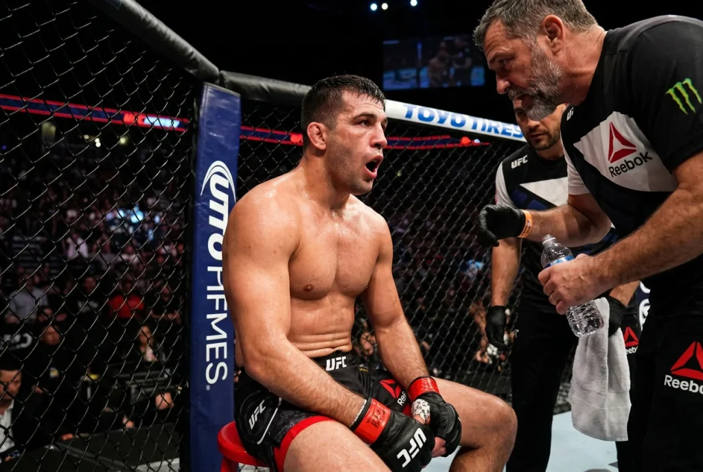 Combattant UFC respirant fortement entre deux rounds, les mains sur les hanches